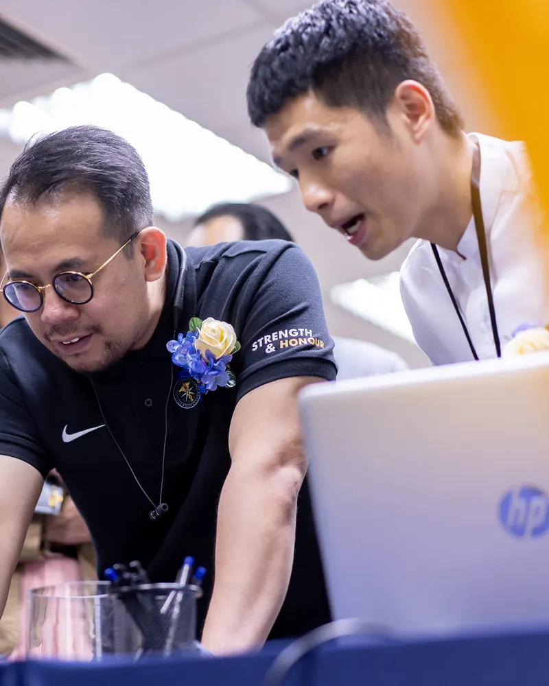 Aaron Lim at a laptop with a guest at the DE/TECH Conference 2018